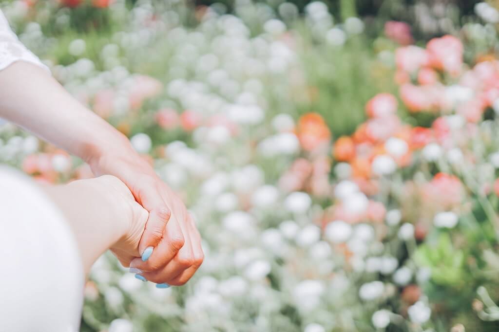 花畑で手をつなぐカップル